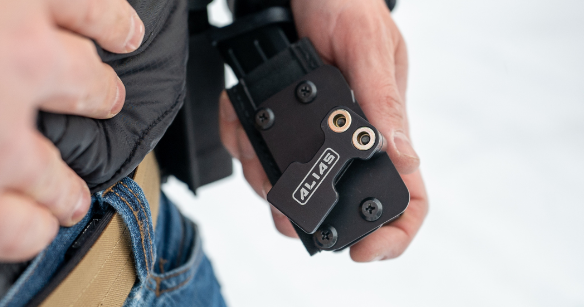 A man attaching a magazine to his tactical belt using the Alias Receiver modular carry system.
